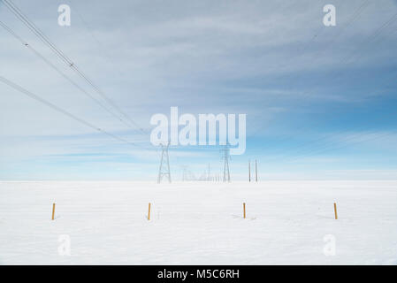 Alberta, Kanada. Blick nach unten Mitte der Zweireihige von Strommasten/Getriebe Türme auf den Prärien im Winter. Stockfoto