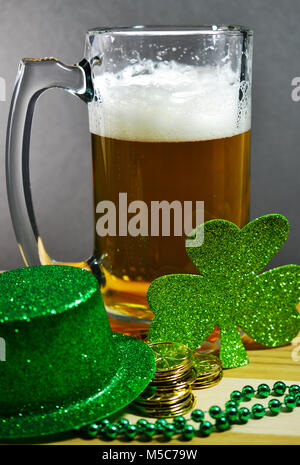 St Patrick's Day Glas Bierkrug gefüllt mit Bier zeigen eine schöne Schaumkrone. Grünen Klee, grün Hut und grüne Perlen auch gezeigt. Stockfoto