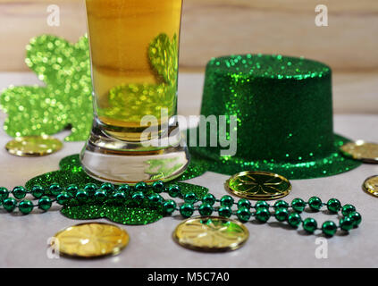 St Patrick's Day Bier Glas, gefüllt mit Bier, grüne Perlen, Gold Münzen und grünen Hut. Stockfoto