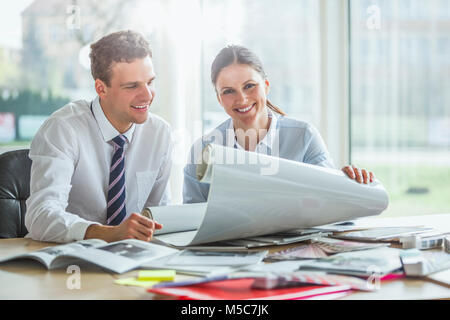 Porträt der jungen weiblichen Architekten mit männlichen Kollegen diskutieren über Blueprint im Büro Schreibtisch Stockfoto