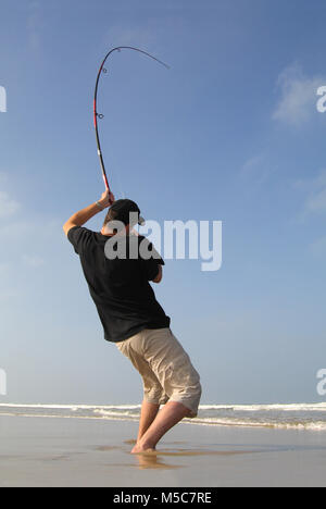 Surf Fischer kämpfen ein Fisch am Strand, Angeln Szene. Die Stange verbiegen Stockfoto