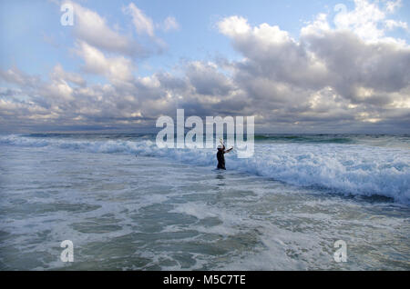 Surf Fischer in die Wellen. Angeln Szene. Surf Casting. Stockfoto