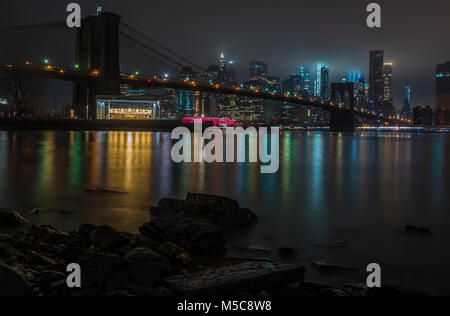 New York City Skyline von Manhattan und Brooklyn Bridge bei Nacht über den Hudson River Stockfoto