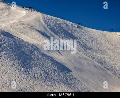 Steilen Gradienten Piste in den italienischen Alpen mit lone Experte snowboarder Position nach unten, gegen einen schönen blauen Himmel - Pila, Vale d'Aosta, Italien Stockfoto