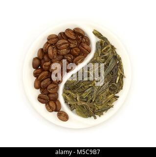 Grüner Tee und gerösteten Kaffeebohnen in Runde Yin und Yang weiße Untertasse auf weißem Hintergrund Stockfoto