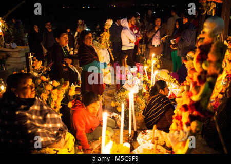 Leute schauen auf dekorierten Gräber auf der Insel Janitzio während Dia de los Muertos (Tag der Toten) feiern in See Patzcuaro, in der Nähe von Patzcuaro, Michoacán, Mexiko am Samstag, 1. November 2014. Dia de los Muertos (Tag der Toten) ist ein traditionelles Urlaub um erinnern und würdigt verstorbenen Familienmitglieder zentriert. Weit davon entfernt, eine düstere Angelegenheit, Dia de los Muetros ist eine Feier des Lebens. Patzcuaro, einer malerischen Stadt im Bundesstaat Michoacán, Mexiko (sieben Stunden westlich von Mexiko Stadt), zieht Touristen aus der ganzen Welt in den Tagen vor dem Dia de los Muertos. Stockfoto