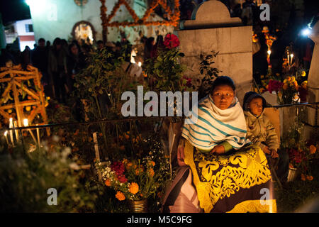 Leute schauen auf dekorierten Gräber auf der Insel Janitzio während Dia de los Muertos (Tag der Toten) feiern in See Patzcuaro, in der Nähe von Patzcuaro, Michoacán, Mexiko am Samstag, 1. November 2014. Dia de los Muertos (Tag der Toten) ist ein traditionelles Urlaub um erinnern und würdigt verstorbenen Familienmitglieder zentriert. Weit davon entfernt, eine düstere Angelegenheit, Dia de los Muetros ist eine Feier des Lebens. Patzcuaro, einer malerischen Stadt im Bundesstaat Michoacán, Mexiko (sieben Stunden westlich von Mexiko Stadt), zieht Touristen aus der ganzen Welt in den Tagen vor dem Dia de los Muertos. Stockfoto