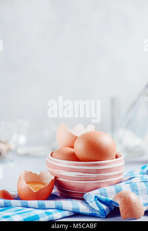 Braune Eier in eine keramische Schüssel auf einen hellen Hintergrund mit Milch, Mehl und Zutaten für Ostern kochen. High-key-Hintergrund mit kopieren. Stockfoto