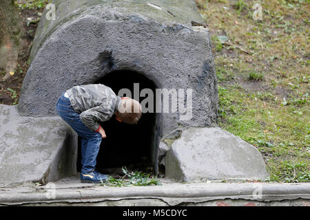 Belarus, die Stadt Gomel, 3. Juni 2017. Tag der Unabhängigkeit in Weißrussland. Der junge blickt in den Abgrund. Interesse an dem Unbekannten. Schatzsuche. neugierige Junge Stockfoto