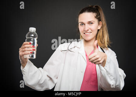 Weibliche Ernährungssachversta5ndiger, Flasche Wasser wie auf schwarzem Hintergrund Stockfoto