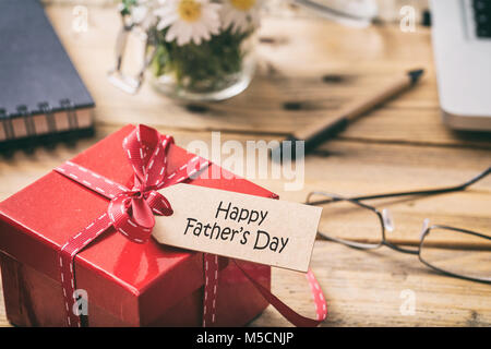 Vatertag Konzept. Roter Geschenkbox mit roter Schleife und glückliche Väter Tag Tag, blur Büro Schreibtisch Hintergrund Stockfoto