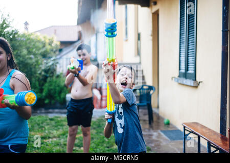 Kinder spielen im Garten mit Pistolen und Gewehre an einem sonnigen Sommertag viel Spaß Stockfoto