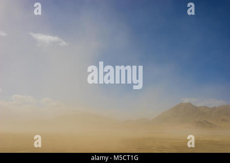 Wind sand driftet durch den Himmel vor Felsen und Sand Bergen in Kalifornien Wüste geblasen. Stockfoto