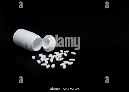 Weiße Pillen und weiße Flasche auf schwarzem Hintergrund. Mit der Kopie im Hintergrund. Für Gesundheit und medizinische Industrie Konzept verwendet. Stockfoto