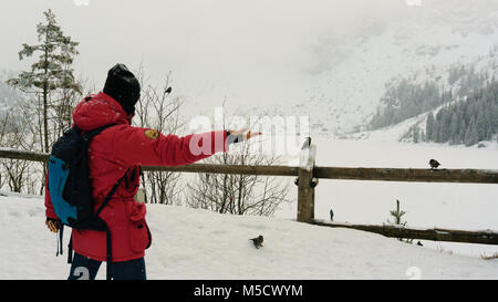 Der Mann feeds Nussknacker in der Nähe von Sea eye See Stockfoto