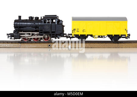 Elektrische Güterzug durch eine alte Dampflokomotive und eine gelbe Boxcar auf den Schienen gebildet Stockfoto
