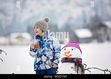 Familie mit Kindern, Gebäude Schneemann in den Park im kleinen Dorf in Österreich, schöne Landschaft Stockfoto