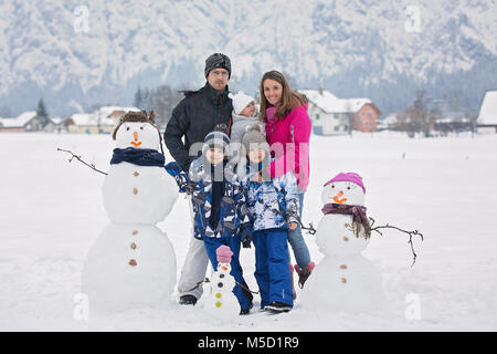 Familie mit Kindern, Gebäude Schneemann in den Park im kleinen Dorf in Österreich, schöne Landschaft Stockfoto