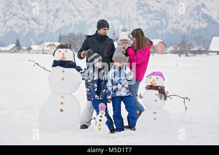 Familie mit Kindern, Gebäude Schneemann in den Park im kleinen Dorf in Österreich, schöne Landschaft Stockfoto