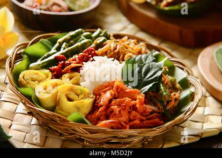 Nasi Campur Bali. Beliebte traditionelle balinesische Gericht aus gedämpftem Reis mit verschiedenen Beilagen serviert. Stockfoto