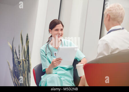 Lächelnd weibliche Krankenschwester mit Zwischenablage sprechen in dem Krankenhaus, Arzt Stockfoto