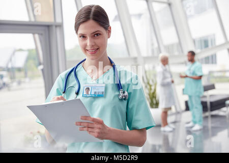 Porträt Lächeln, selbstbewussten weiblichen Krankenschwester mit Zwischenablage im Krankenhaus Stockfoto