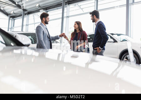 Autoverkäufer, die Autoschlüssel an Kunden in Auto Dealership showroom Stockfoto