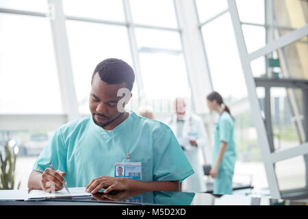 Männliche Krankenschwester Überprüfung von Patientenakten im Krankenhaus Lobby Stockfoto