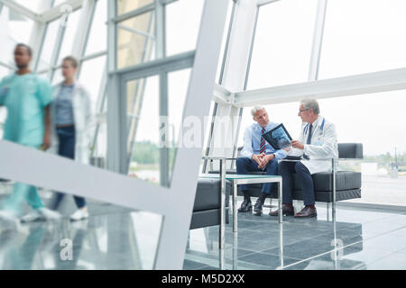 Männliche Chirurgen mit x-ray im Gespräch mit Patient im Krankenhaus Lobby Stockfoto