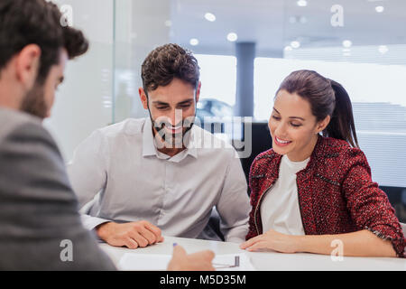 Autoverkäufer erklären Finanzkontrakt Schreibarbeit paar Kunden im Autohaus Büro Stockfoto