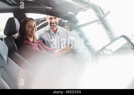 Porträt Lächeln Autoverkäufer und weibliche Kunden im Fahrersitz der neuen Auto im Autohaus Stockfoto