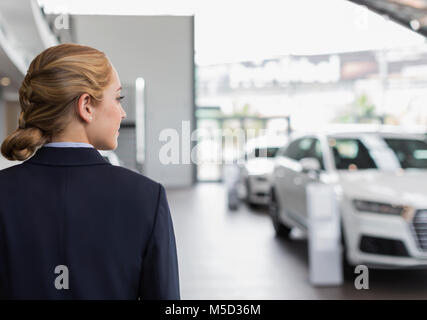 Blond auto Verkäuferin sie Suchen in Auto Dealership showroom Stockfoto