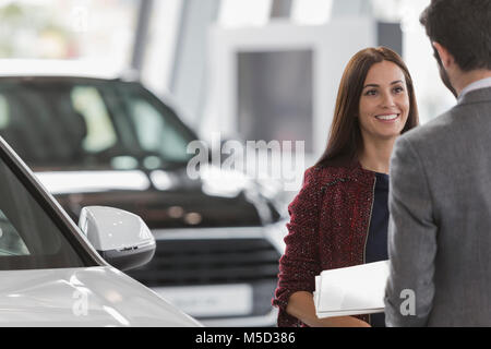 Lächelnd weibliche Kunden hören Autoverkäufer in Auto Dealership showroom Stockfoto