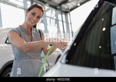 Porträt Lächeln, selbstbewussten weiblichen Kunden laden hybrid Auto Auto Dealership showroom Stockfoto