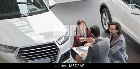 Autoverkäufer Händeschütteln mit weiblichen Kunden im Auto Dealership showroom Stockfoto