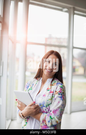 Portrait von lächelnden jungen Geschäftsfrau holding Tablet PC im Büro Stockfoto