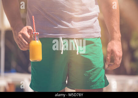 Mann mit kleinen Glas Flasche frischen Orangensaft mit Trinkhalm im Freien Stockfoto