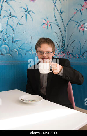 Eine junge glücklich und zuversichtlich, dass Menschen mit Down-Syndrom an einem Tisch in einem Cafe sitzt Stockfoto