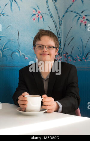 Eine junge glücklich und zuversichtlich, dass Menschen mit Down-Syndrom an einem Tisch in einem Cafe sitzt Stockfoto