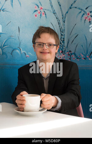 Eine junge glücklich und zuversichtlich, dass Menschen mit Down-Syndrom an einem Tisch in einem Cafe sitzt Stockfoto