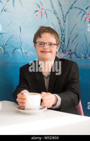 Eine junge glücklich und zuversichtlich, dass Menschen mit Down-Syndrom an einem Tisch in einem Cafe sitzt Stockfoto