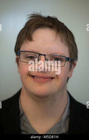 Ein junger Mann mit Down-syndrom sitzt an einem Tisch in einem Cafe Kaffee trinken Stockfoto