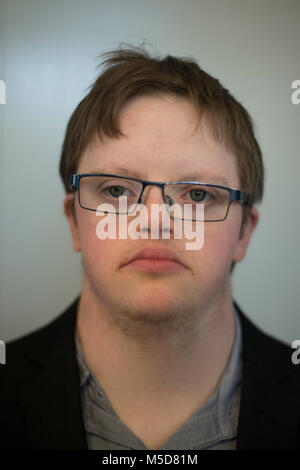 Ein junger Mann mit Down-syndrom sitzt an einem Tisch in einem Cafe Kaffee trinken Stockfoto