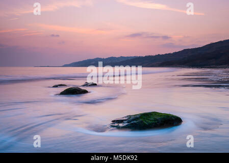 Charmouth, Dorset, Großbritannien. 22. Februar 2018. UK Wetter. Eine trübe rosa Sonnenuntergang vom Strand gesehen bei Charmouth auf der Jurassic Coast von Dorset in Lyme Regis in der Ferne. Foto: Graham Jagd-/Alamy Leben Nachrichten. Stockfoto