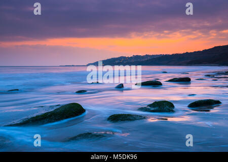 Charmouth, Dorset, Großbritannien. 22. Februar 2018. UK Wetter. Eine trübe Sonnenuntergang vom Strand gesehen bei Charmouth auf der Jurassic Coast von Dorset in Lyme Regis in der Ferne. Foto: Graham Jagd-/Alamy Leben Nachrichten. Stockfoto