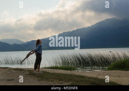 Seine Arme am Ufer des Sees geöffnet, drehte sein Gesicht in den Wind, eine einsame junge Frau, Stockfoto