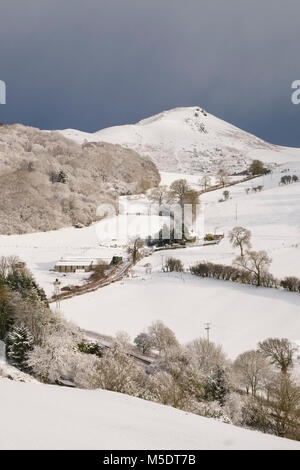 Helmeth Hill und Caer Caradoc Hill aus gesehen Hazler Hügel gesehen fallenden Schnee im Winter, Church Stretton, Shropshire, Großbritannien Stockfoto