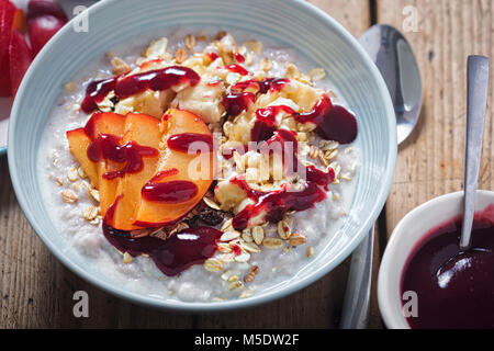 Erdbeere Porridge mit Hafer, zerdrückte Banane und Pflaumen und Heidelbeeren Sauce Stockfoto