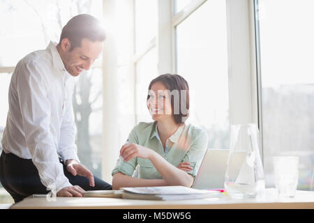 Glückliche junge Unternehmer diskutieren am Schreibtisch im Büro Stockfoto