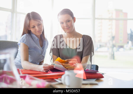 Porträt der jungen Geschäftsfrau mit weiblichen Kollegen diskutieren über Fabric swatches im Büro Stockfoto